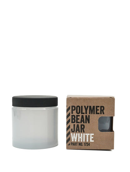 En hvid gennemskinnelig krukke med sort låg er ved siden af en brun æske mærket "Polymer Bean Jar med låg, Hvid." Æsken har en udskæring, der afslører en del af fødevaresikker-krukken, der viser dets slanke Comandante C40-inspirerede design.