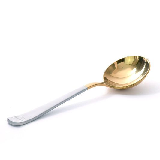 Brewista Professional Cupping Spoon i Titanium Gold med et slankt hvidt håndtag ligger på en hvid overflade. Dens runde, dybe skål reflekterer lyset strålende, med Brewista-logoet subtilt nær bunden.