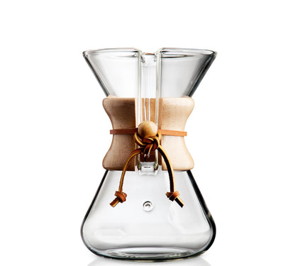 Chemex kaffebrygger 5-kopper (CM-2) er lavet af håndlavet glas med timeglasdesign, med en trækrave og lædersnysning for perfekt hældningsteknik. Den elegante og funktionelle kaffemaskine er isoleret på en hvid baggrund.