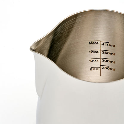 Rhino Coffee Gear Skummekande Pro, lavet af fødevaregodkendt rustfrit stål, har en slank tud og indvendige volumenmål på 8-14 oz (250-410 ml). Dets minimalistiske hvide design forbedrer dets professionelle look.