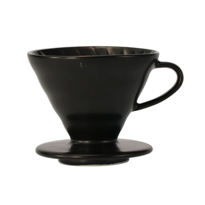 Hario Keramisk Drip Tragt er en sort, konisk kaffedrypper med sidehåndtag, perfekt til præcis kaffeekstraktion i pour-over brygning. Dens design ligner HARIO V60 og har en flad base for stabilitet på kopper eller kander, hvilket giver enestående smagskontrol.