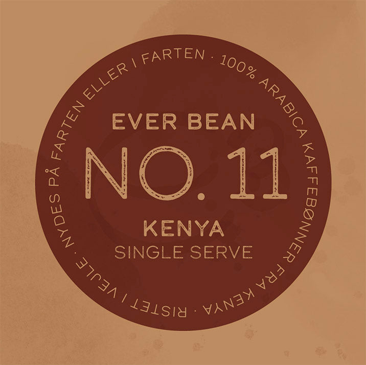 En brun cirkulær kaffeetiket lyder: "EverBean Single Serve No. 11, Kenya." I omgivende tekst står der: "100% Arabica kaffebønner fra Kenya. Specialkaffe ristet i Vintae. Nydes på farten eller i farten.