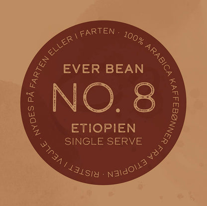 En brun cirkulær etiket centrerer teksten "EverBean Single Serve" og langs kanten står "100% Arabica kaffebønner fra Etiopien" plus "Nydes på farten eller i farten", hvilket markerer den som en specialkaffe, der er ideel til kaffeelskere på farten.